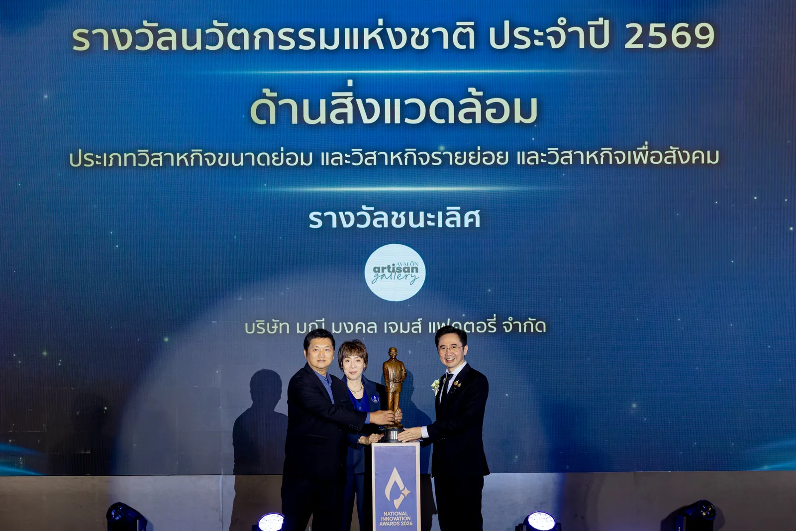 On stage at the award moment, with the screen naming the Environment award and the company