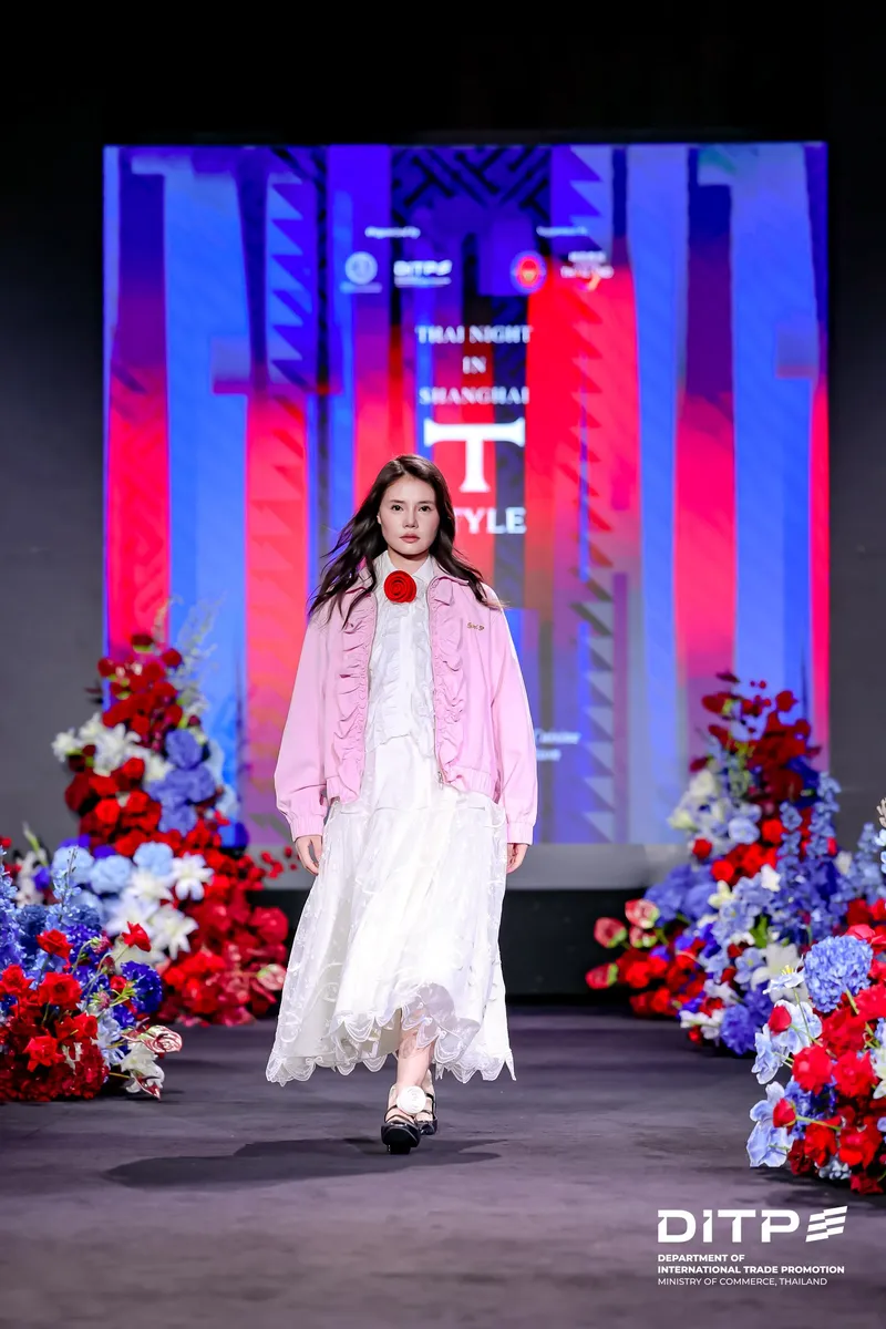 A model in a pink jacket and white dress