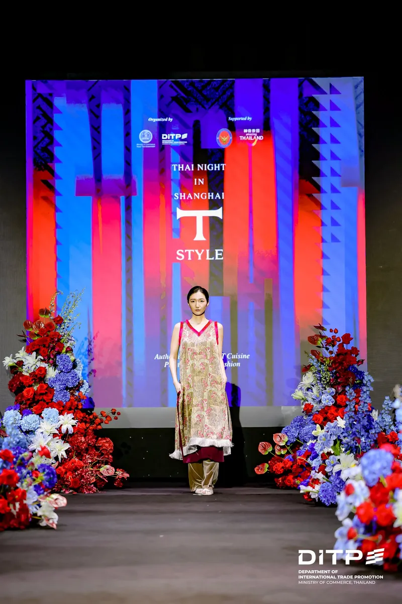 A model in a long patterned dress in front of the T-STYLE screen