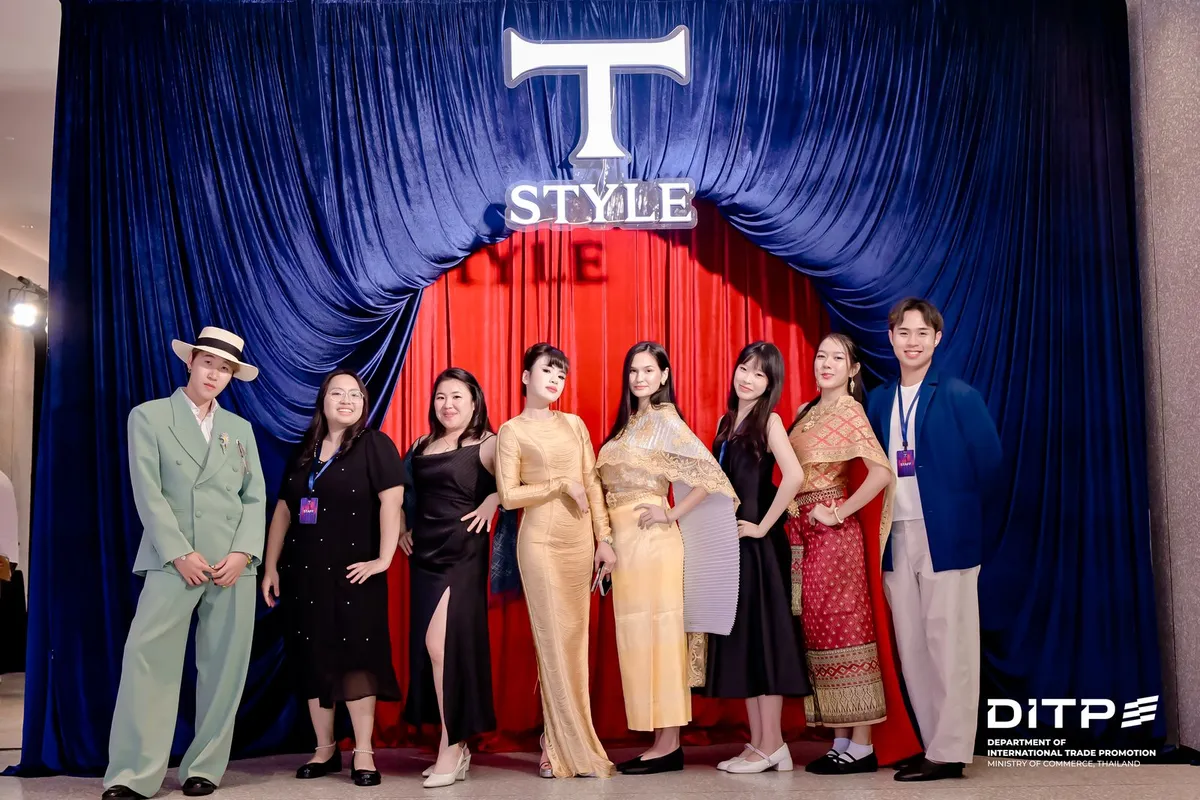 Guests in Thai-style outfits in front of the T-STYLE curtain