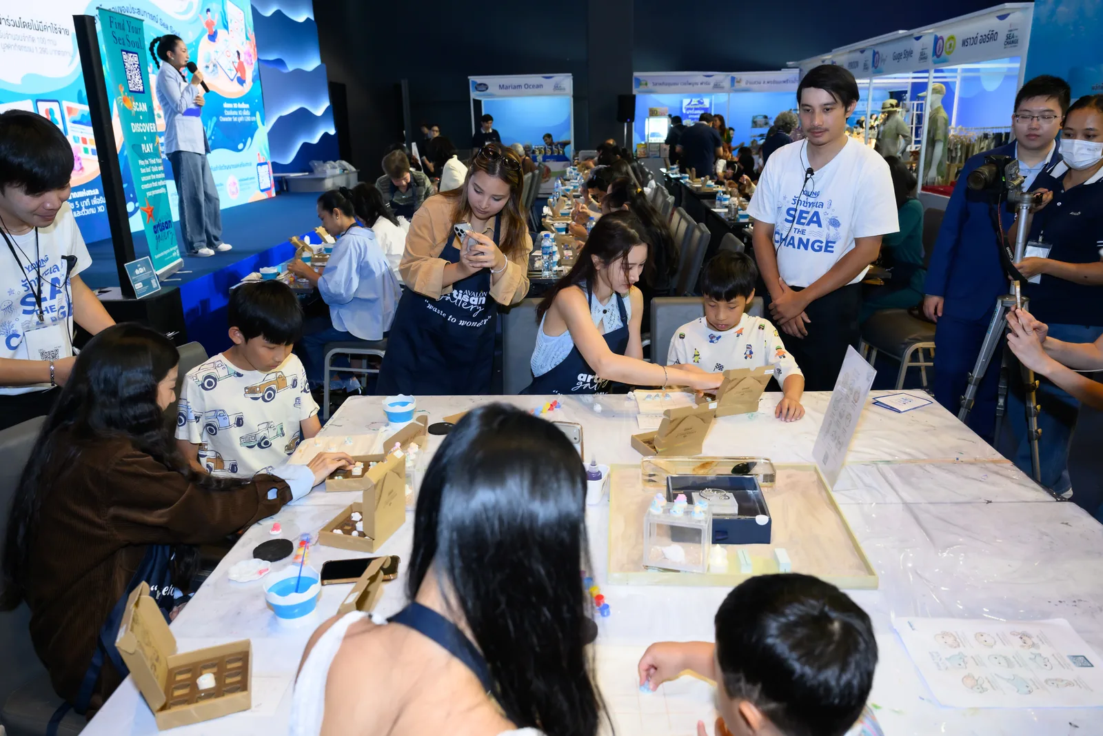Families paint MyraShell sea creatures at the workshop tables